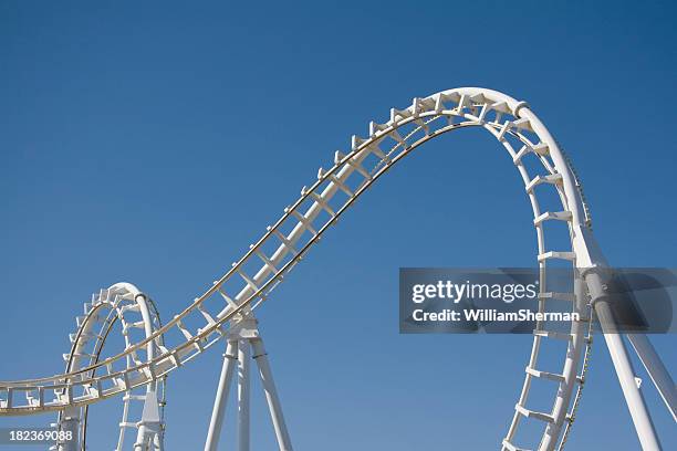 white rollercoaster loops against a clear blue sky - achtbaan stockfoto's en -beelden