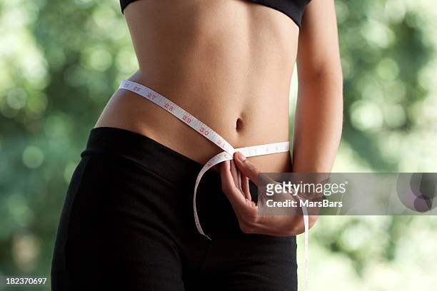 slim woman measuring waist - waist stockfoto's en -beelden
