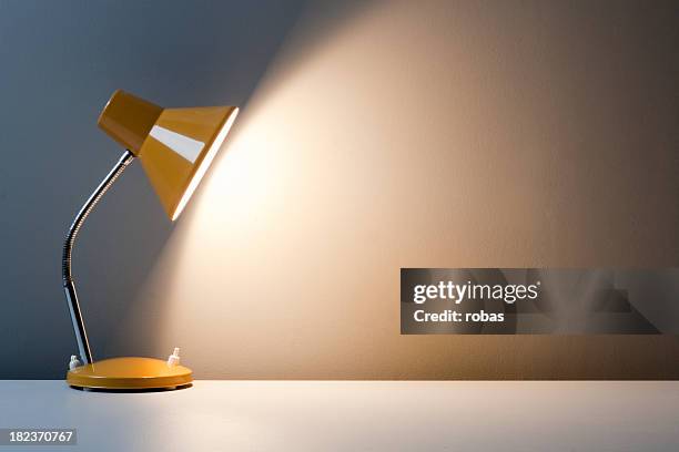 profile of yellow desk lamp, turned on on white table - lamp stock pictures, royalty-free photos & images