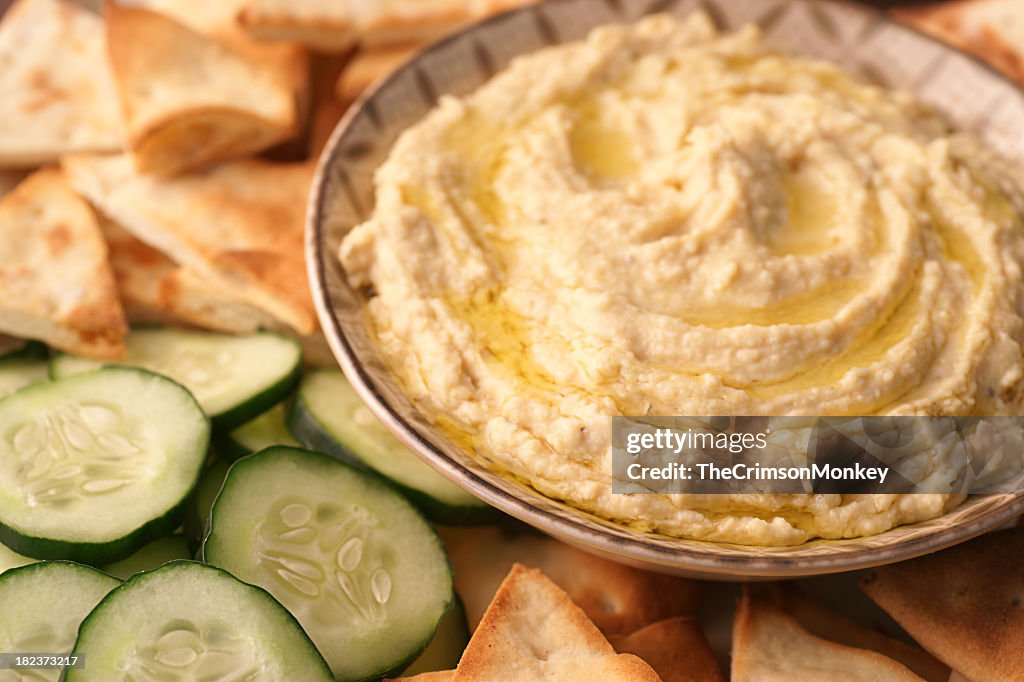 A bowl of fresh hummus and cucumbers