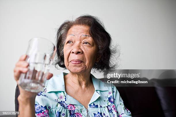 senior black woman holding a glass of water - filipino ethnicity and female not male 個照片及圖片檔