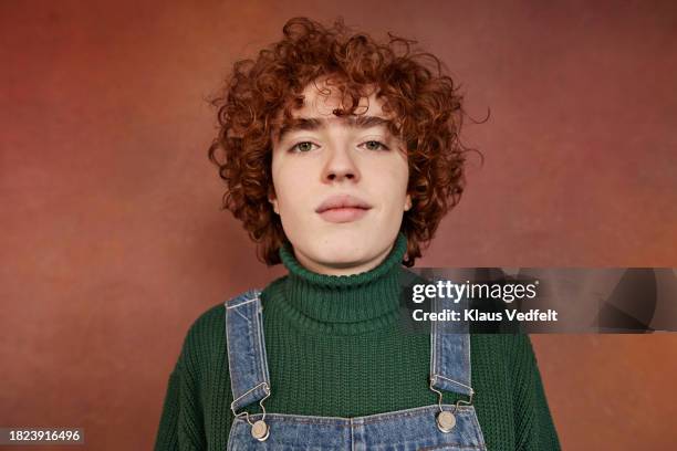 portrait of teenage boy with curly wearing turtleneck against brown background - one teenage boy only stock pictures, royalty-free photos & images