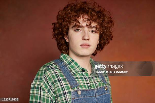 portrait of redhead teenage boy with curly hair against brown background - one teenage boy only stock pictures, royalty-free photos & images