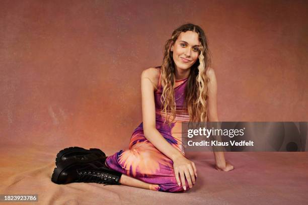 portrait of smiling teenage girl with long hair sitting against brown backdrop - brown shoe stock pictures, royalty-free photos & images