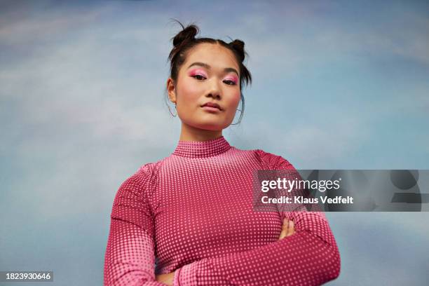 portrait of confident teenage girl with arms crossed against colored background - empowered stock-fotos und bilder