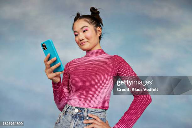 teenage girl using mobile phone while standing against colored background - digital native stock-fotos und bilder