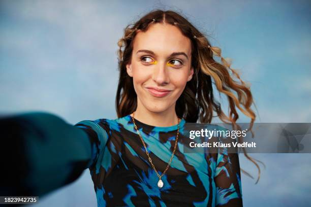 smiling teenage transgender girl looking away against colored background - imatura imagens e fotografias de stock