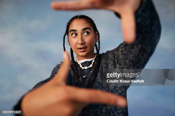 non-binary person gesturing finger frame while standing against colored background - arab woman fashion ストックフォトと画像