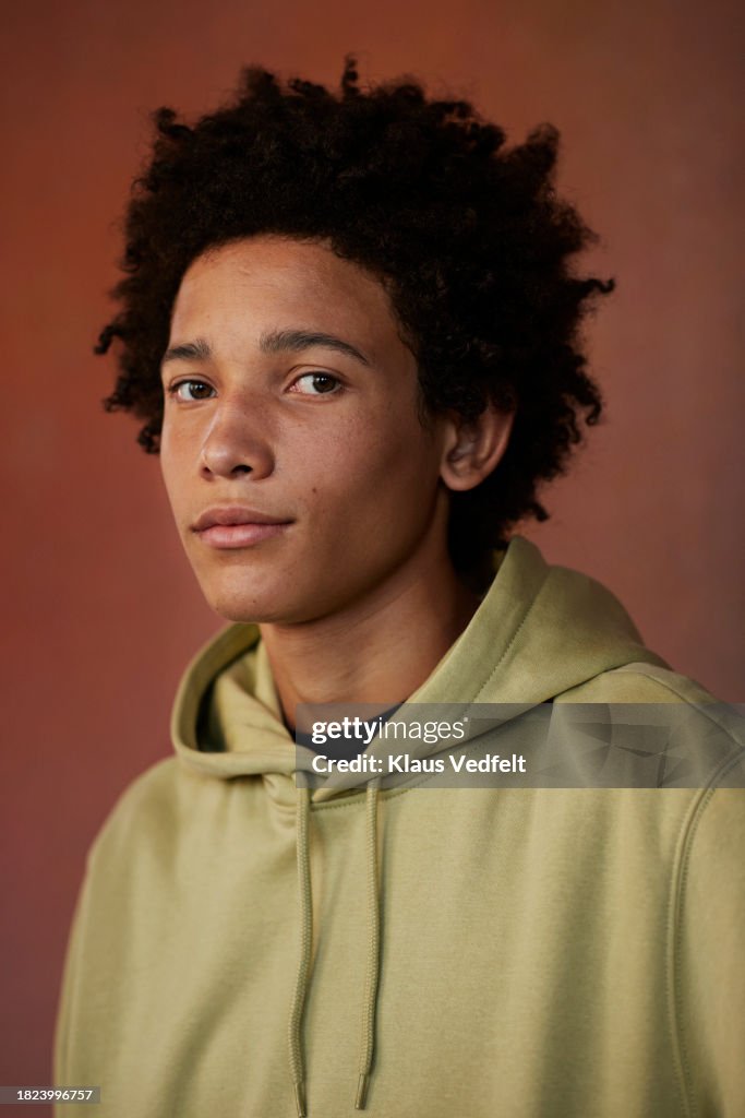 Portrait of teenage boy with blank expression against brown background