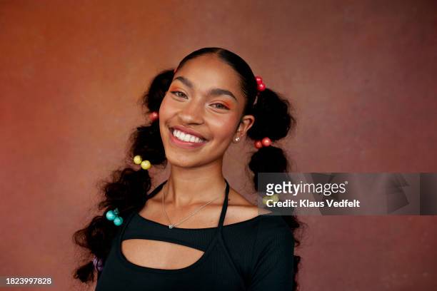 portrait of smiling teenage girl with braided hair against brown background - beauty girl stock pictures, royalty-free photos & images