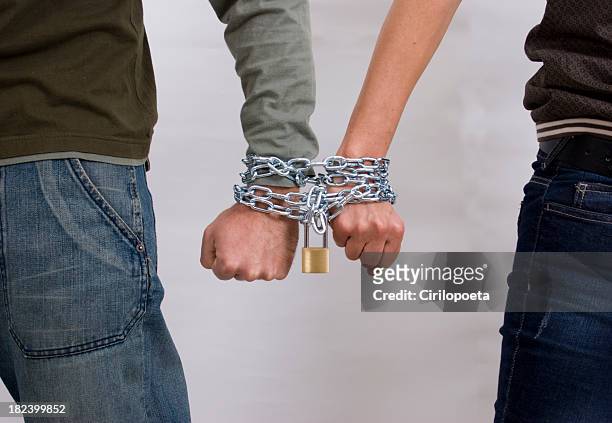 male and female hand locked in chains - verslaving stockfoto's en -beelden