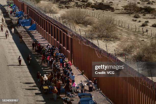 Asylum seekers line up to receive food at a makeshift camp after crossing the nearby border with Mexico near the Jacumba Hot Springs on November 28,...