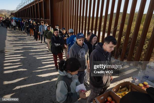 Asylum seekers line up to receive food at a makeshift camp after crossing the nearby border with Mexico near the Jacumba Hot Springs on November 28,...