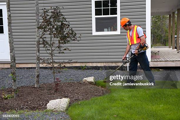 man trims grass wearing safety equipment - mowing lawn stock pictures, royalty-free photos & images