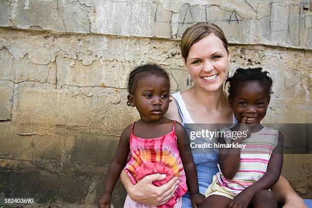 american woman holding african girls - orphan child stock pictures, royalty-free photos & images