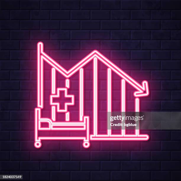 ilustraciones, imágenes clip art, dibujos animados e iconos de stock de gráfico de disminución de la capacidad de camas hospitalarias. icono de neón brillante sobre fondo de pared de ladrillo - urgencias-hospital