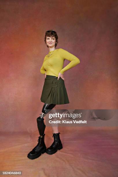 teenage girl with prosthetic leg and hands on hips standing against brown backdrop - brown shoe stock pictures, royalty-free photos & images