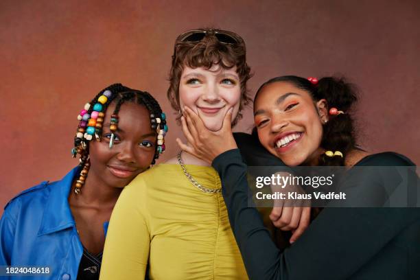 happy teenage female friends standing against brown background - teenagers only stock pictures, royalty-free photos & images