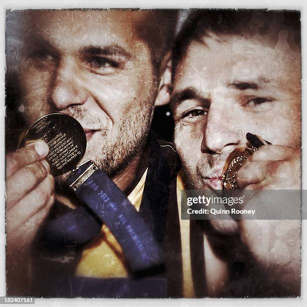 Lance Franklin and Brent Guerra of the Hawks kiss their Premiership Medallions after the Hawks won the 2013 AFL Grand Final match between the...