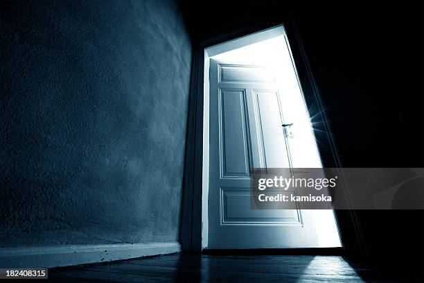 dark hallway with an opened door with bright light coming in - a haunted house stockfoto's en -beelden