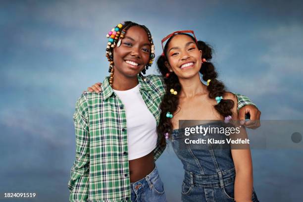 portrait of smiling female friends with arms around standing against colored background - plaid shirt isolated stock pictures, royalty-free photos & images