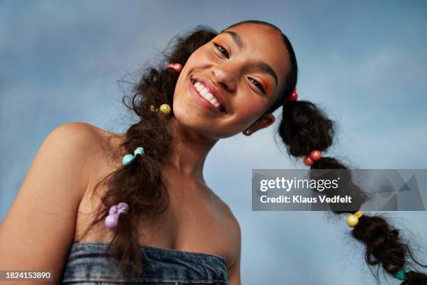 portrait of smiling teenage girl with head cocked against colored background - braid hairstyle stock pictures, royalty-free photos & images