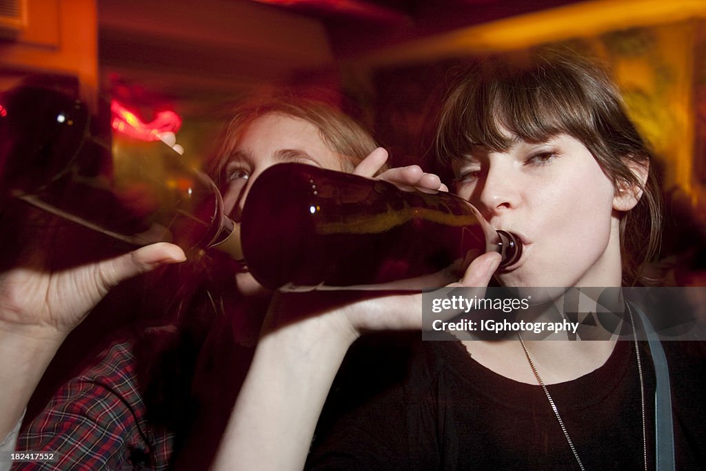 Two Attractive Young Women Drinking Beers at a Bar