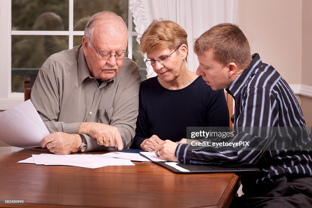 Financial advisor with senior couple going over paperwork