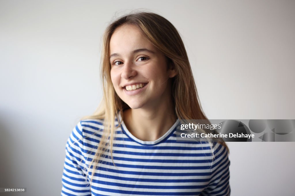 Portrait of a beautiful 18 year old young woman in front of a grey background