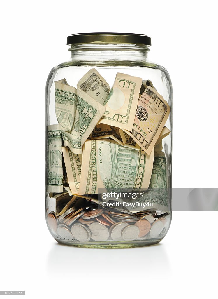 A clear glass jar filled with cash and coins
