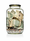 A clear glass jar filled with cash and coins 