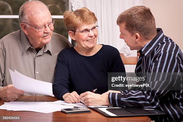 man giving financial advisor to senior couple smiling - inheritance tax stock pictures, royalty-free photos & images