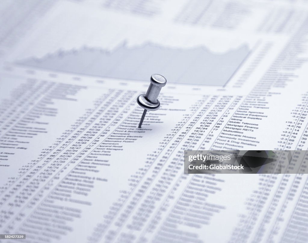 Push pin on financial newspaper