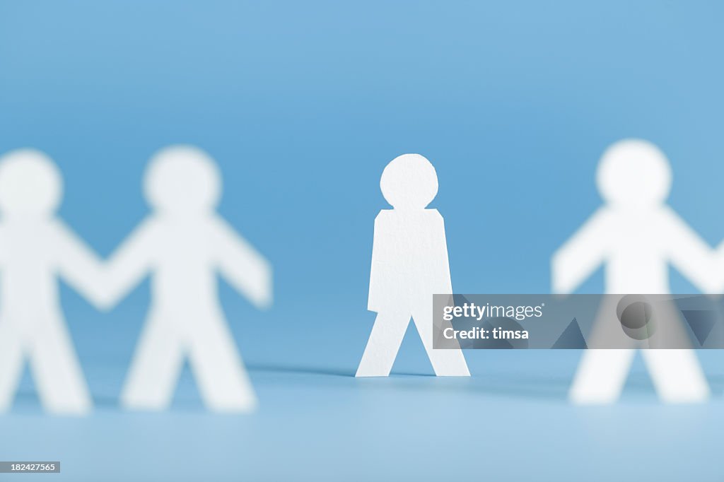 Paper figures holding hands with one alone not participating