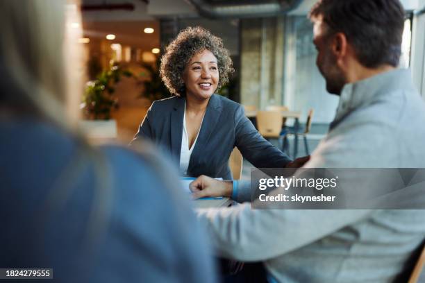 happy insurance agent talking to her customers in the office. - bankers stock pictures, royalty-free photos & images