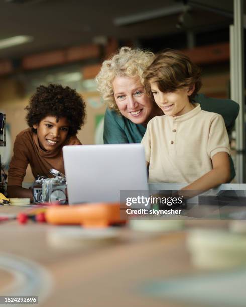 happy teacher and schoolboys using laptop in laboratory. - school project stock pictures, royalty-free photos & images