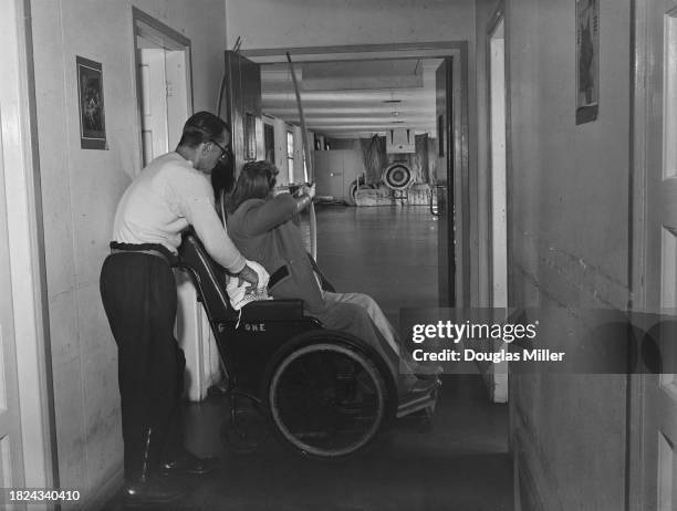 Woman in a wheelchair practicing archery at Stoke Mandeville Hospital, Buckinghamshire, September 1948. Sport was a major method of therapy for...