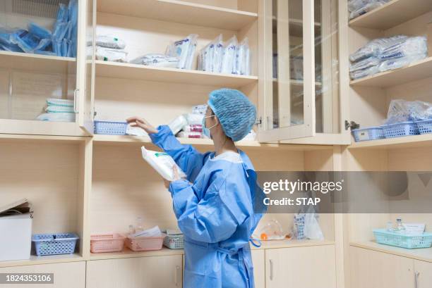 a medical worker is taking medical supplies from the shelf - medische artikelen stockfoto's en -beelden