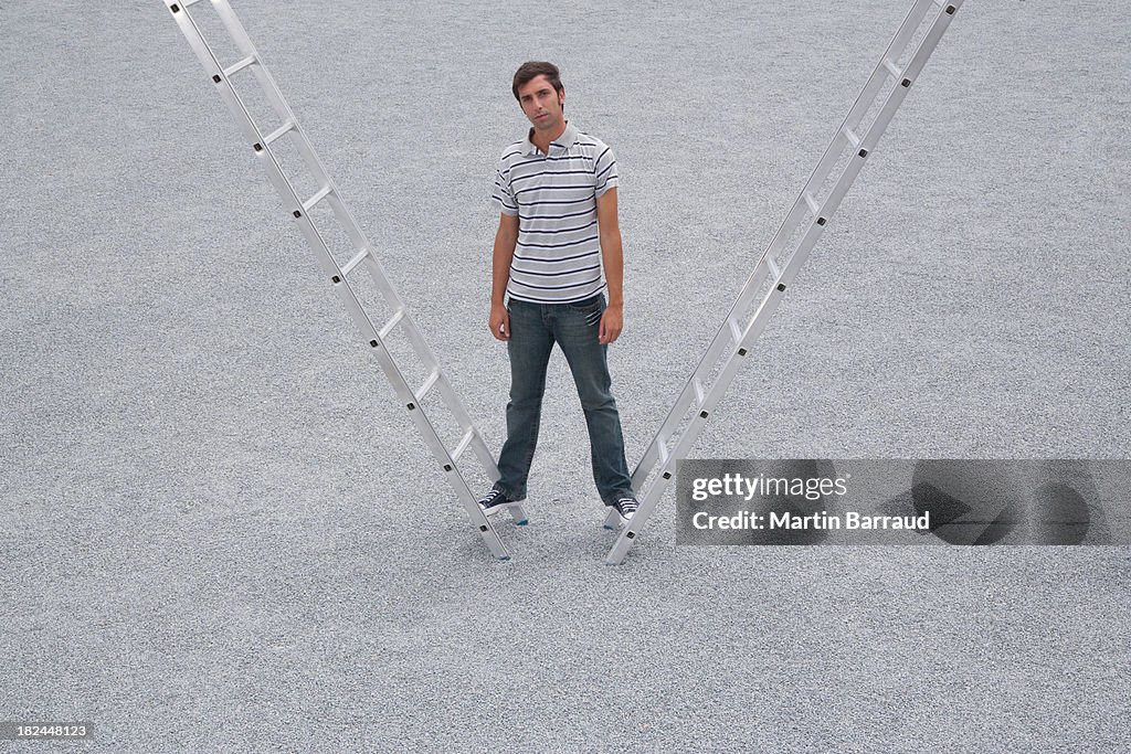 Man standing standing outdoors on two ladders