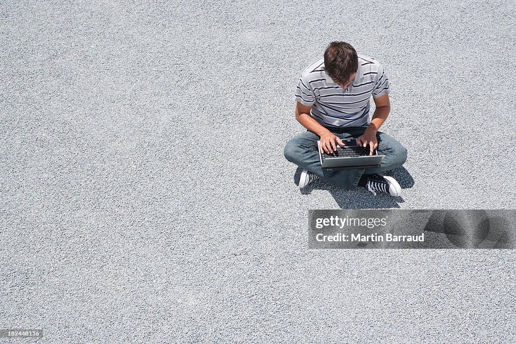 Man sitting on the ground working on his laptop computer