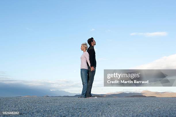 mann und frau stehen rücken an rücken - man and woman holding hands profile stock-fotos und bilder