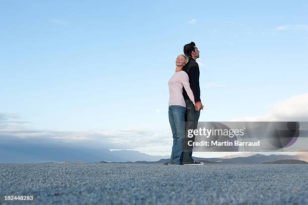 man and woman standing back-to-back - man and woman holding hands profile stockfoto's en -beelden