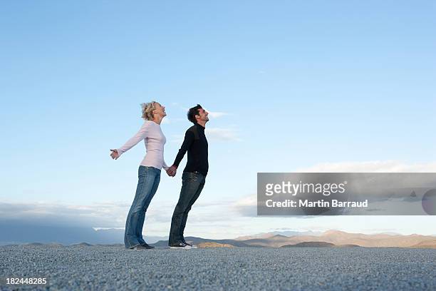 man and woman leaning into the wind - leaning stock pictures, royalty-free photos & images