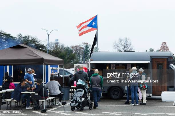 Customers wait for food at Lechonera DMV food truck photographed in Woodbridge, Virginia on December 2, 2023. .