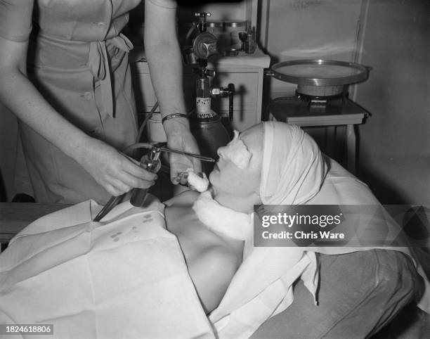 Beautician spraying oxygen onto a client's face during oxylation treatment at Helena Rubinstein's London salon, April 1948.