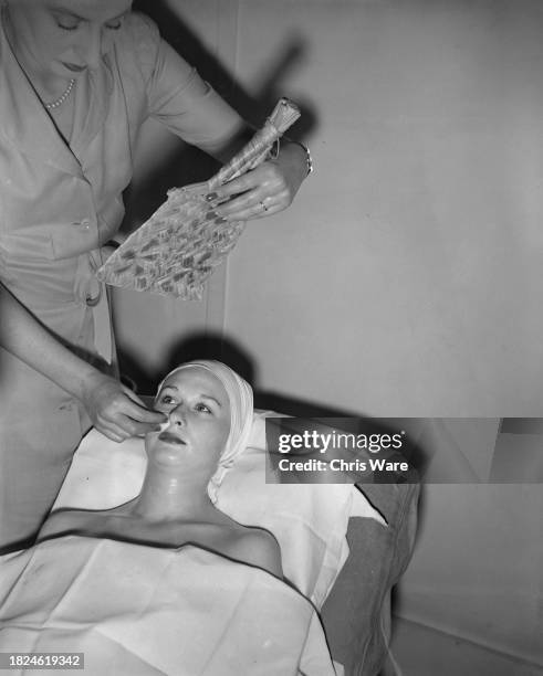 Beautician fanning a female client's face during a beauty treatment at Helena Rubinstein's London salon, April 1948.