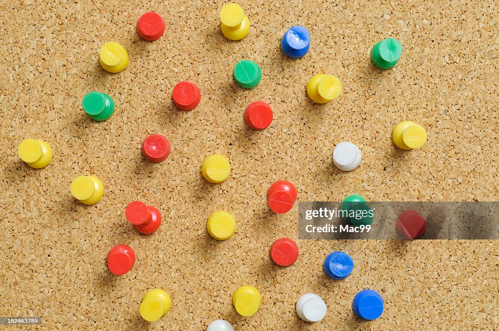 Cork board with red yellow green and white drawing pins