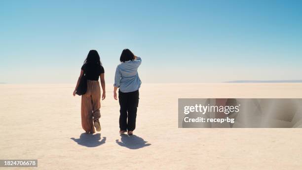 two multi-ethnic female tourist friends walking and exploring the tuz gölü salt lake in anatolia region of türkiye turkey - 2 people back asian imagens e fotografias de stock