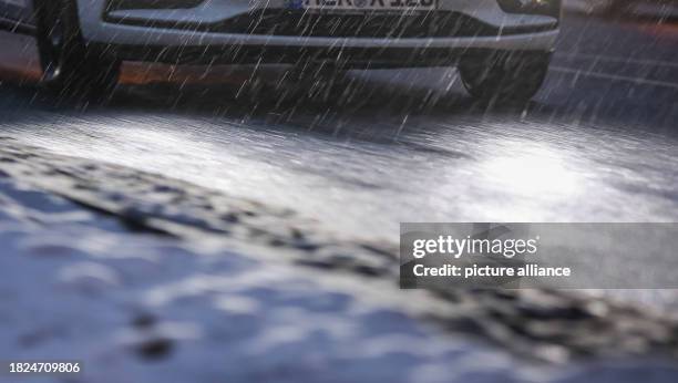 December 2023, Saxony, Leipzig: A car drives towards the city center in the morning in the rain and slippery snow. It is expected to continue snowing...