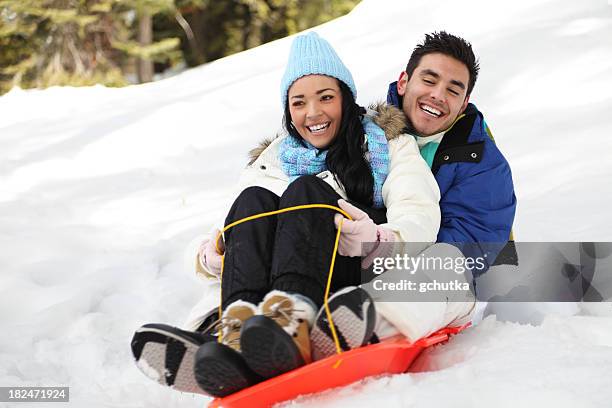 couple sledding in the snow - sports and recreation stock pictures, royalty-free photos & images